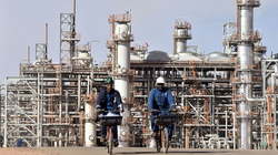 Hai công nhân bên ngoài một cơ sở sản xuất khí đốt ở Algeria (Ảnh: AFP).