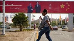 Một phụ nữ bước qua con đường, nơi có áp phích chào đón chuyến thăm của Chủ tịch Trung Quốc Tập Cận Bình ở Papua New Guinea năm 2018 (Ảnh: AP).