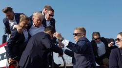 Cựu Tổng thống Donald Trump được các nhân viên Sở Mật vụ bảo vệ ra khỏi sân khấu (Ảnh: Getty)