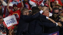 Donald Trump được nhân viên Mật vụ dẫn đi sau khi có tiếng súng vang lên tại cuộc vận động tranh cử ở Butler, Pennsylvania (Ảnh: AFP)