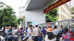 Phụ huynh học sinh đứng chờ con ở điểm thi. Ảnh: Minh Thúy