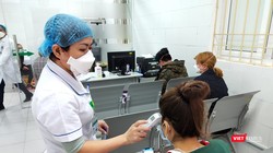 Bác sĩ đo nhiệt độ cơ thể cho người bệnh. Ảnh: Minh Thúy