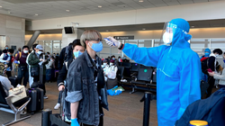 Nhân viên y tế đo thân nhiệt cho hành khách trên chuyến bay. Ảnh: BYT 