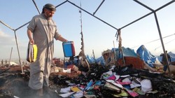 Người đàn ông bên đống tro tàn còn lại của trại tị nạn sau khi trúng không kích. Ảnh: Getty