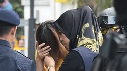 Nghi phạm Đoàn Thị Hương (áo vàng) che mặt khi bị cảnh sát áp giải tới phiên tòa. (Ảnh: AFP)