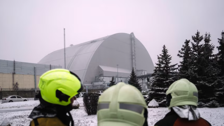 Nhân viên cứu hộ theo dõi mọi người kiểm tra thiệt hại ở tấm chắn bức xạ của Lò phản ứng số 4 tại địa điểm Chernobyl sau cuộc tấn công bằng UAV ngày 14/2. Ảnh: Getty.