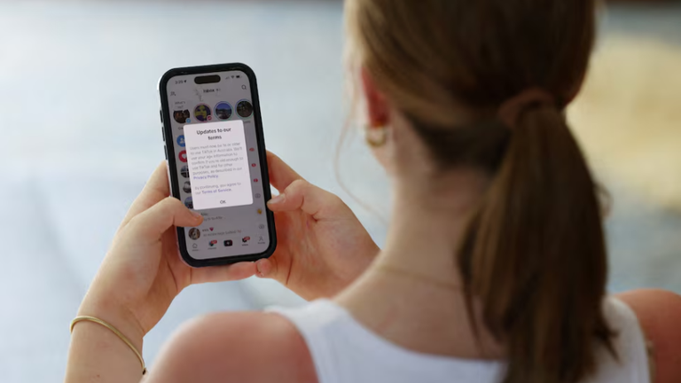 Một thiếu niên với chiếc điện thoại di động hiển thị tin nhắn từ TikTok, trong bối cảnh luật cấm sử dụng mạng xã hội đối với người dùng dưới 16 tuổi ở Australia có hiệu lực, ngày 10/12. Ảnh: Reuters.