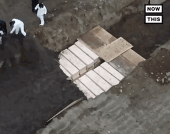 Các tù nhân lấp đất vùi các quan tài trong hố chôn tập thể (Ảnh: Guancha).