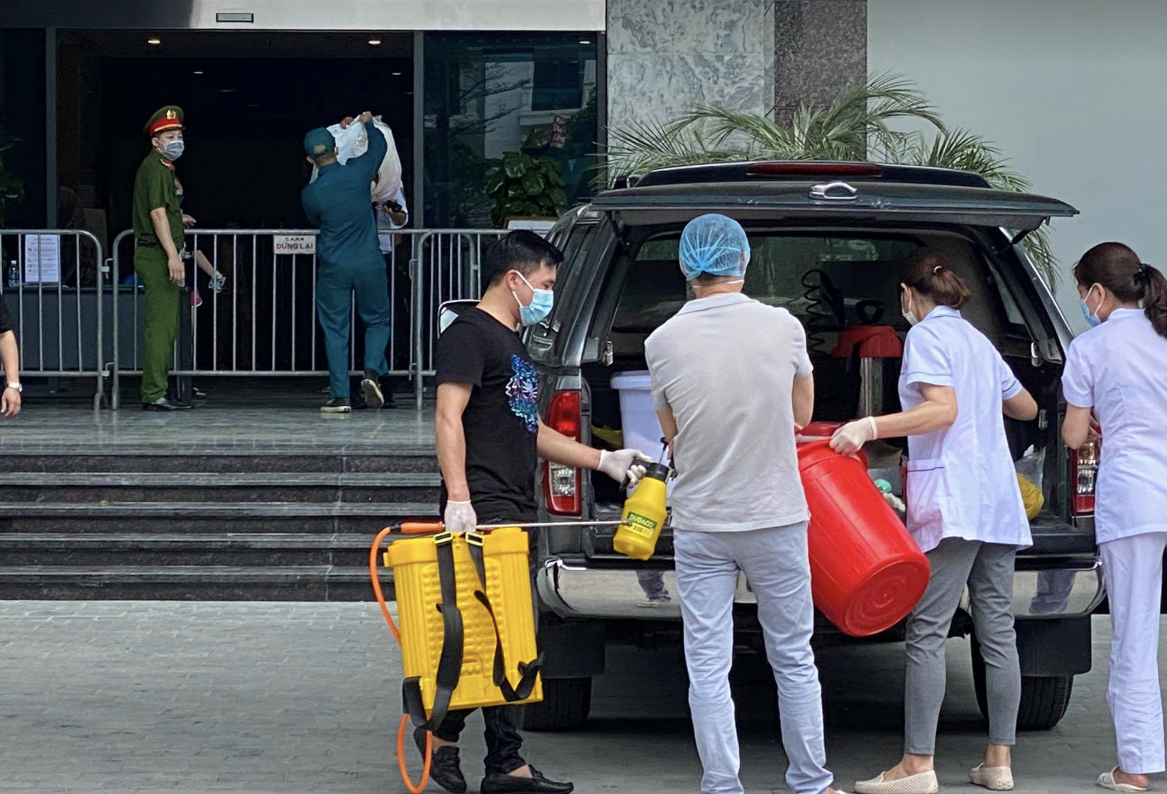 Nhân viên y tế chuẩn bị phun khử khuẩn khu vực quanh chung cư (Ảnh - Hoàng Anh)