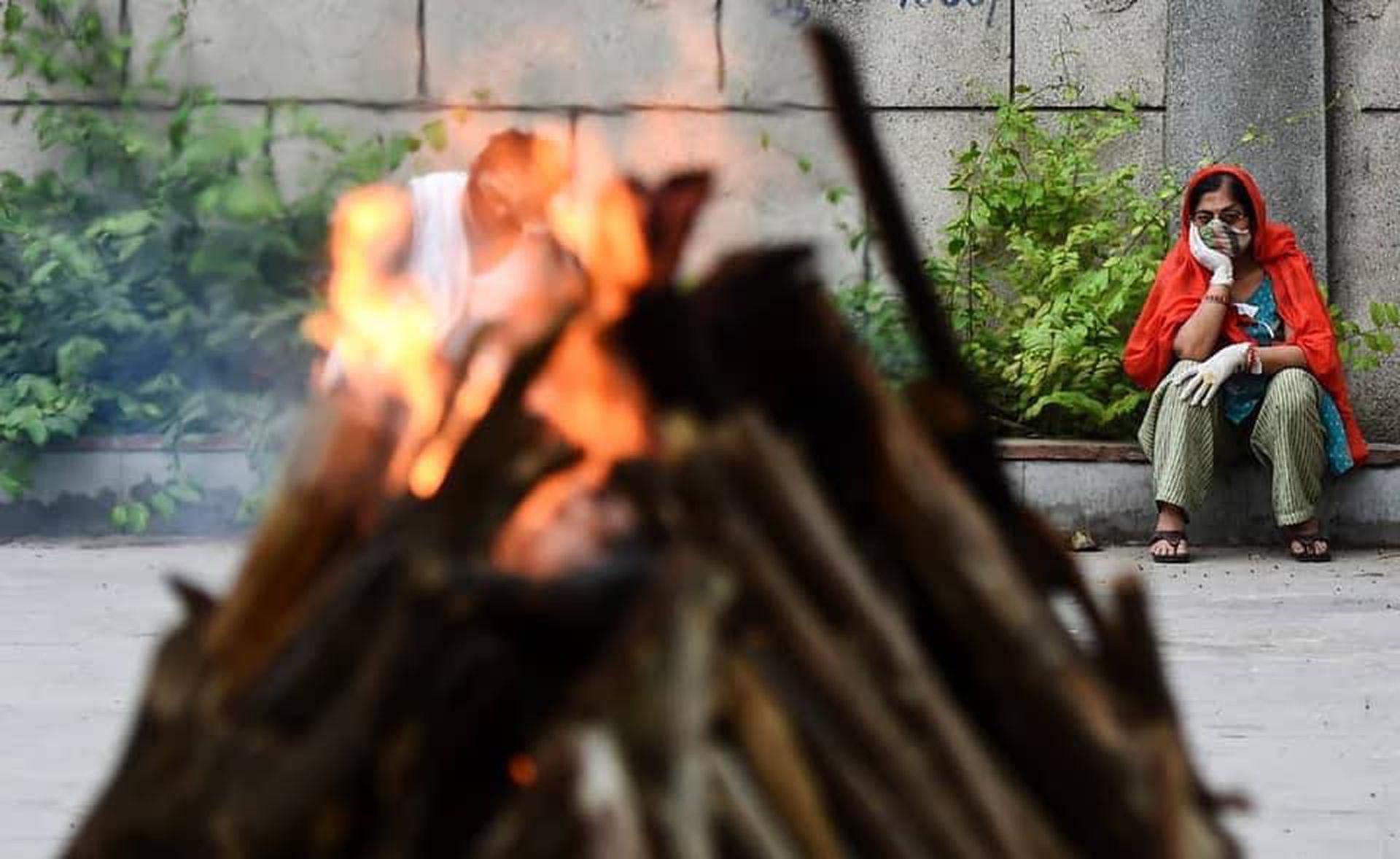 Thân nhân người quá cố ngồi vĩnh biệt người thân trước giàn thiêu (Ảnh: Đa Chiều).