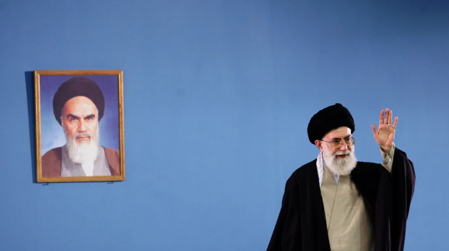 Lãnh tụ tối cao Iran Ayatollah Ali Khamenei đang vẫy tay bên cạnh bức chân dung của cố lãnh tụ sáng lập nước Cộng hòa Hồi giáo Iran Ayatollah Khomeini trong một cuộc họp ở Tehran, ảnh chụp năm 2006. Ảnh: IRNA. Mỹ–Israel và lời đe dọa thay đổi chế độ Iran Những viễn cảnh nào có thể xảy ra 2.png