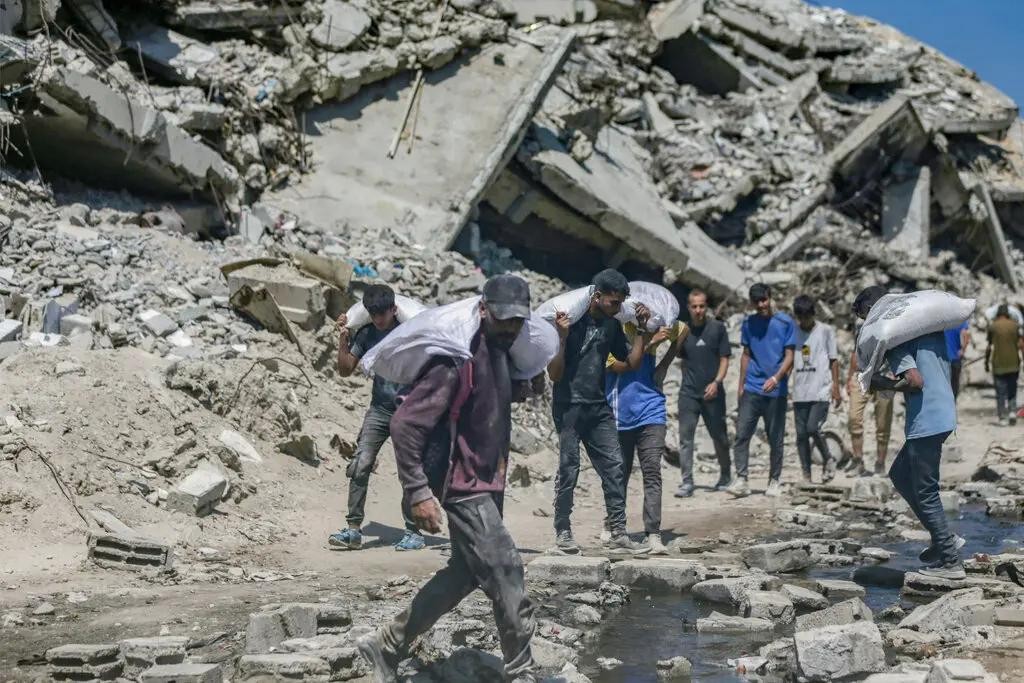 Người dân Palestine ở Gaza mang theo túi hàng cứu trợ. Ảnh: NYTimes. Cái chết thầm lặng ở Gaza Nạn đói, suy dinh dưỡng và sự tuyệt vọng 2.jpg