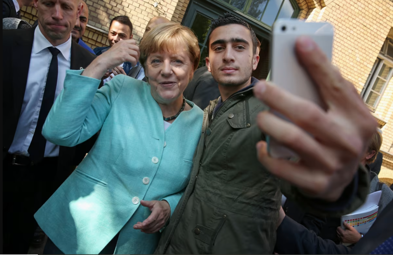 Thủ tướng Đức Angela Merkel chụp ảnh với Anas Modamani, một người tị nạn từ Syria, sau khi bà đến thăm nơi trú ẩn cho người di cư và người tị nạn ở Berlin, Đức vào ngày 10/9/2015. Ảnh: Getty. 10 năm sau quyết định lịch sử mở cửa đón 1 triệu người tị nạn Nước Đức đã đổi thay thế nào.png