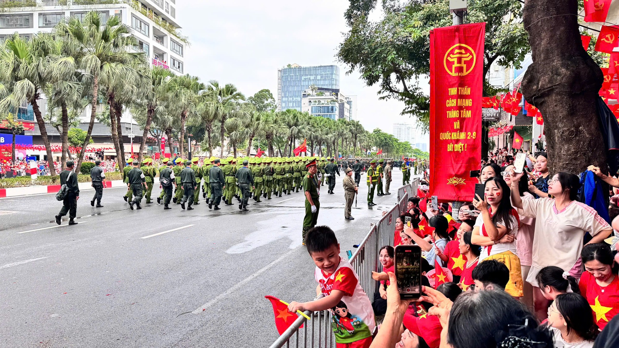 Chị Hằng cùng con nhỏ chăm chú theo dõi từng khối diễu binh đi qua phố Liễu Giai. "Dù phải chờ đợi nhưng tôi thấy rất xứng đáng, các màn diễu binh thật mãn nhãn lắm", chị chia sẻ với nụ cười rạng rỡ. Ảnh: Quỳnh An Anh 1.jpeg