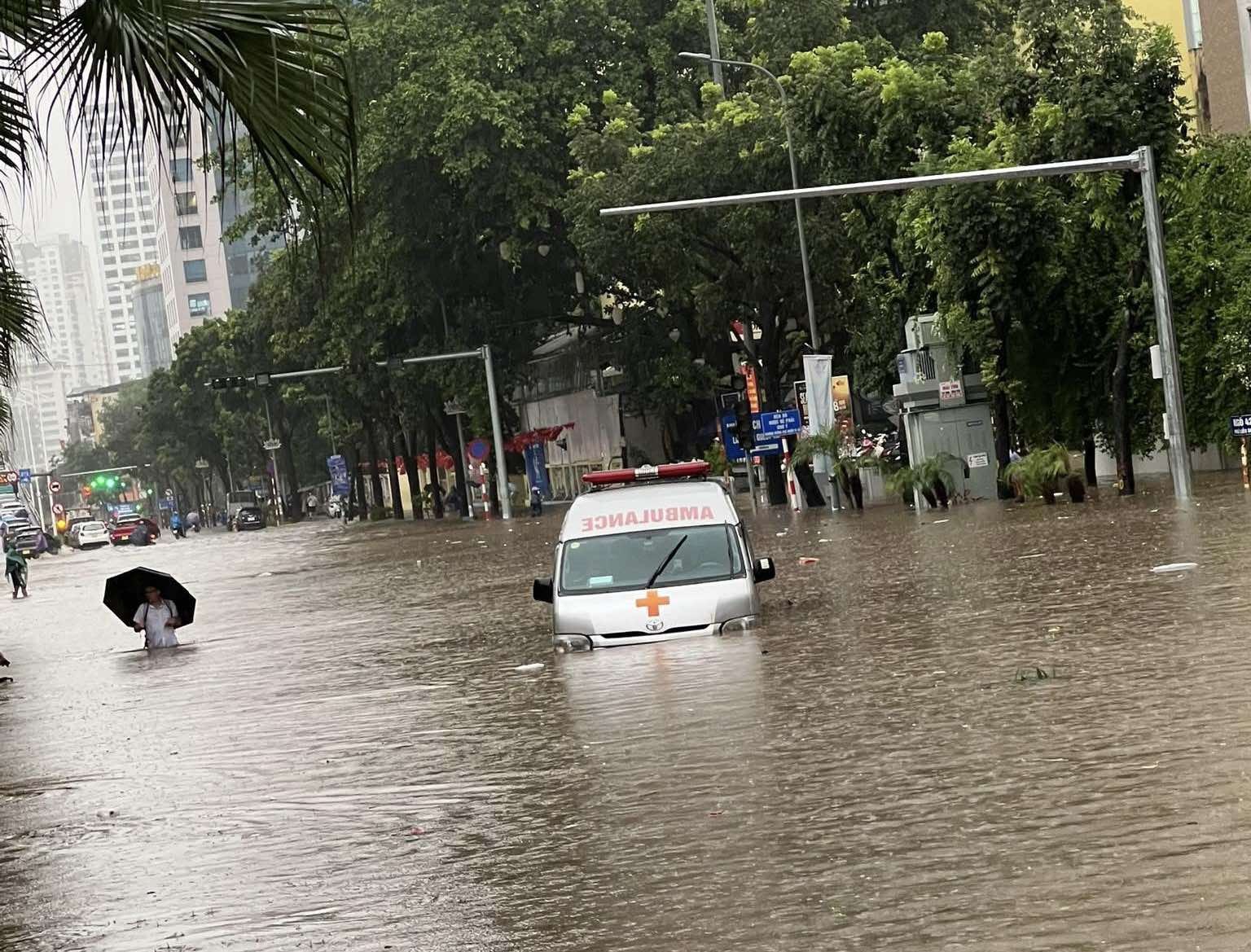 Nước ngập sâu trên tuyến phố Liễu Giai (Hà Nội) khiến giao thông tê liệt, nhiều phương tiện bị chìm một phần trong dòng nước. Một xe cấp cứu cố gắng di chuyển qua đoạn ngập, trong khi người dân lội bộ vật vã. Anh Đăng Phát, nhà ở Hoàng Quốc Việt, cho biết đã bị kẹt lại tại khu vực này từ trưa đến gần 15h do mưa lớn gây ngập nặng. Ảnh: Đăng Phát. Anh 1.jpg