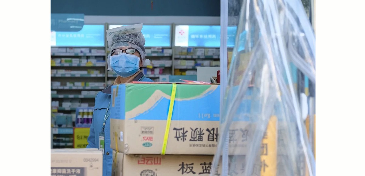 Một nhân viên đeo khẩu trang đứng trong một hiệu thuốc ở Vũ Hán. Ở một số tỉnh, người dân phải đăng ký với tên thật khi mua thuốc trị sốt và ho để các quan chức có thể theo dõi họ (ảnh: AP)