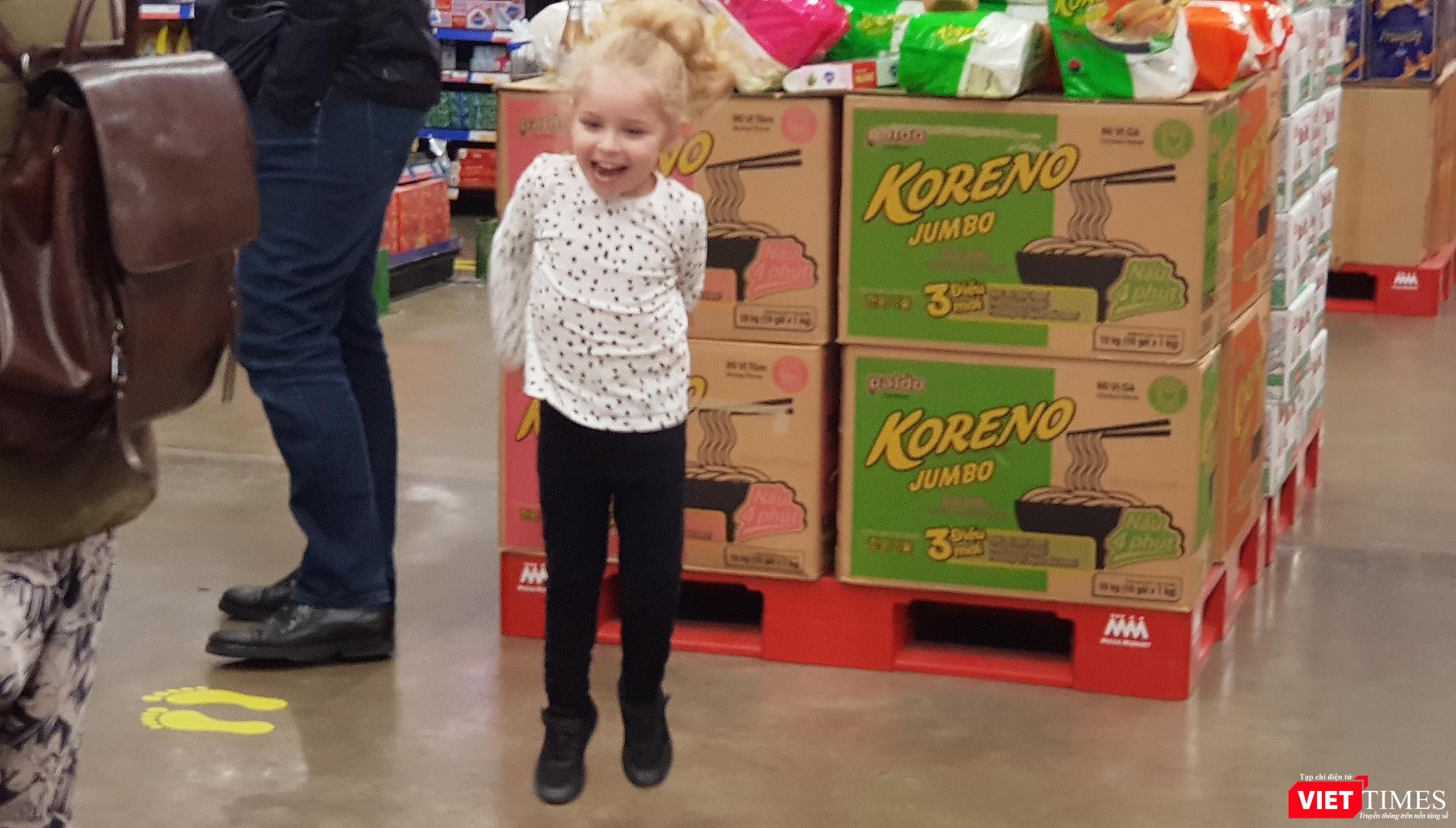 Một bé gái người nước ngoài thích thú chạy nhảy trong siêu thị. Bé gái này thậm chí còn không đeo khẩu trang