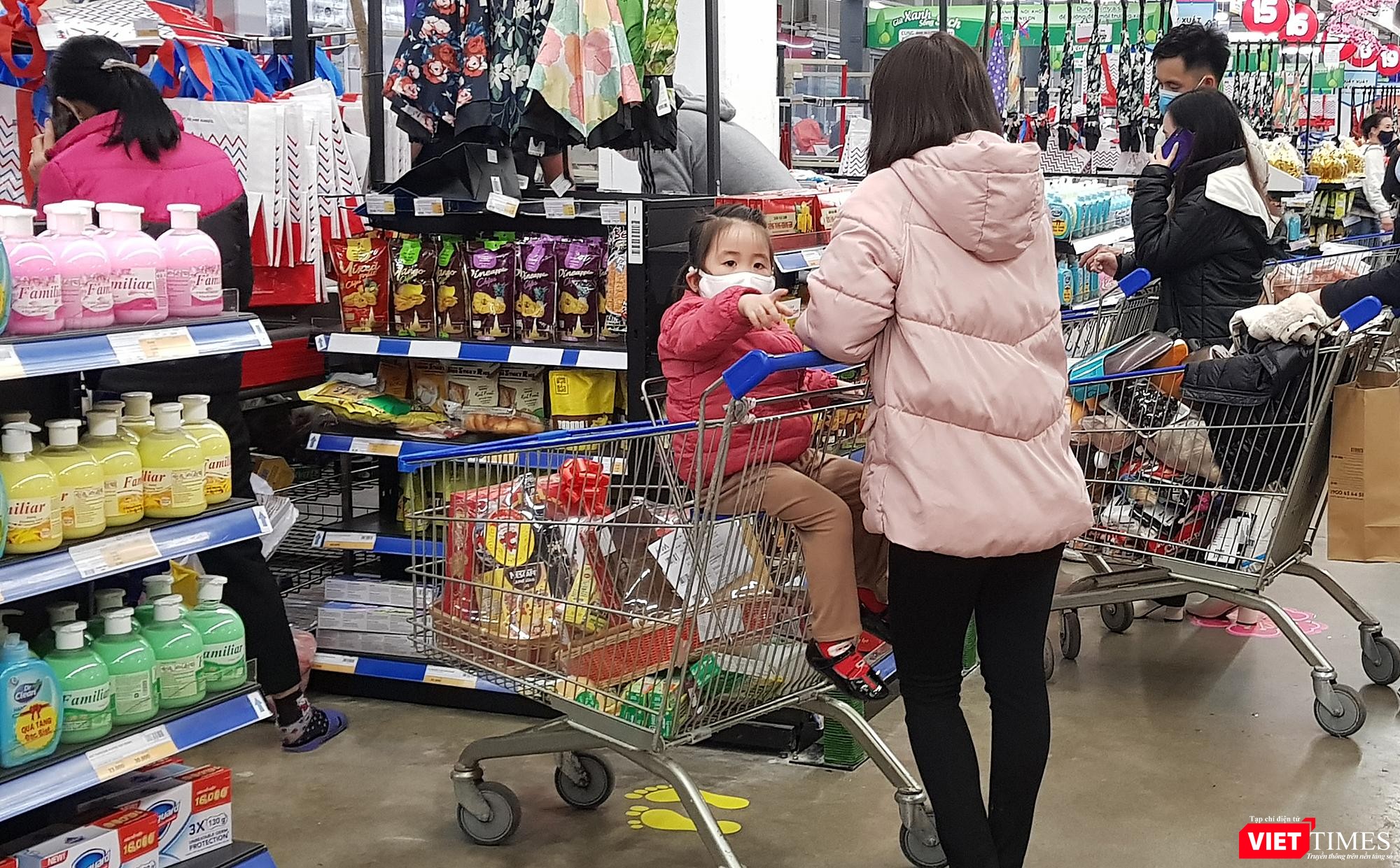 Em bé này chỉ khoảng 3 tuổi, được mẹ đeo khẩu trang và đặt trên xe đẩy hàng