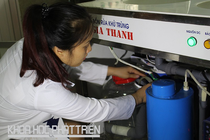 TS Nguyễn Thị Thanh Hải - đồng tác giả Giải pháp hữu ích - bên một thiết bị sản xuất anolit thường dùng trong bệnh viện, trạm y tế, trường học. Ảnh: Phạm Phượng