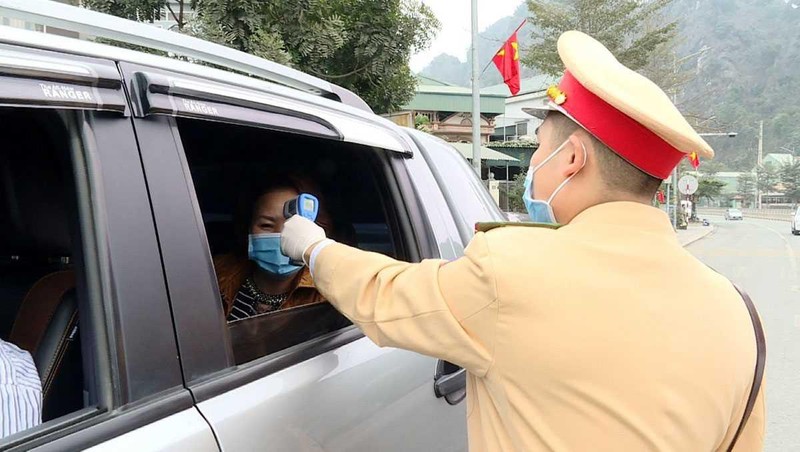 Công an TP Cẩm Phả vừa điều tiết giao thông vừa kết hợp với đo nhiệt độ người tham gia giao thông. Ảnh: UBND tỉnh Quảng Ninh.