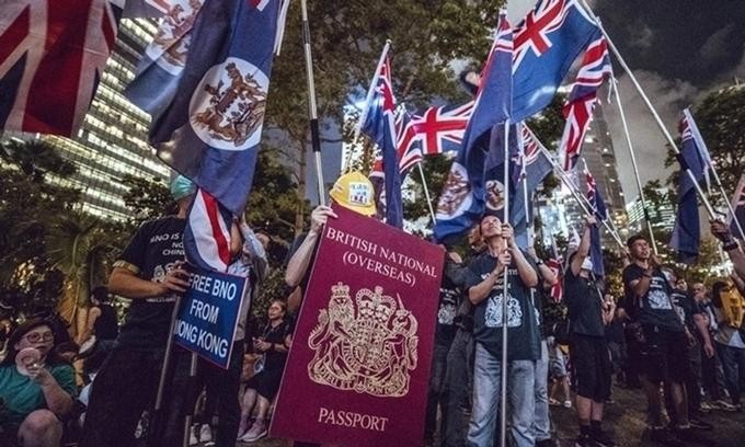 Người biểu tình Hong Kong cầm hình ảnh mô phỏng hộ chiếu hải ngoại Anh cuối tháng 6 (Ảnh: SCMP)