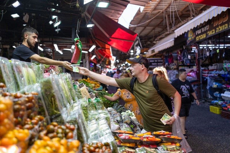 Một khách hàng mua nông sản tại một quầy hàng ở Tel Aviv, Israel (Ảnh: Bloomberg)