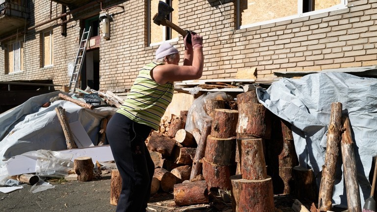 Một phụ nữ Ukraine chặt củi bên ngoài căn hộ của mình (Ảnh: Getty)