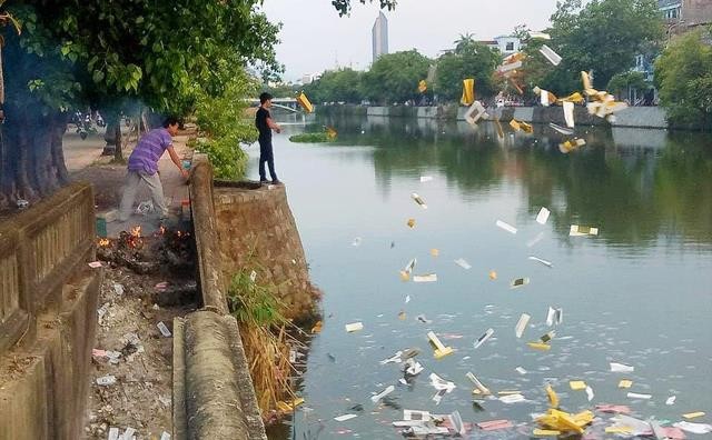 Hai người đàn ông thản nhiên đốt và ném vàng mã xuống sông