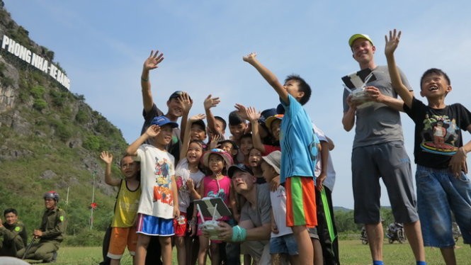 Trẻ em Quảng Bình thích thú theo dõi hai chuyên gia của ABC kiểm tra thiết bị quay phim từ xa (flycam) - Ảnh: Lê Nam