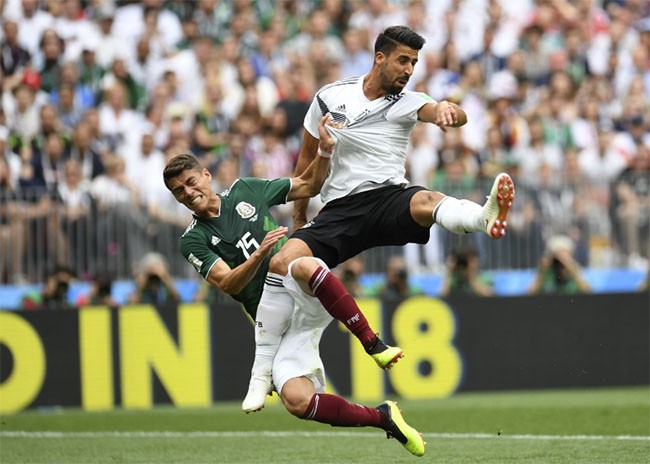 Tiền vệ người Đức Sami Khedira và hậu vệ của Hector Moreno của Mexico ngã sau khi cố gắng đánh đầu.