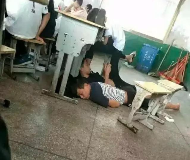 Trong giờ học, hai học sinh lại coi phòng học như phòng ngủ ở nhà, một người thì nằm lăn ra đất ngủ trong khi người kia thì lướt điện thoại với tư thế chân ngang ngược.
