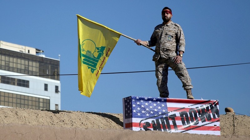 Một lính thuộc lực lượng đặc biệt Quds phất cờ Thánh chiến dẫm trên quốc kỳ Mỹ (Ảnh: Reuters)