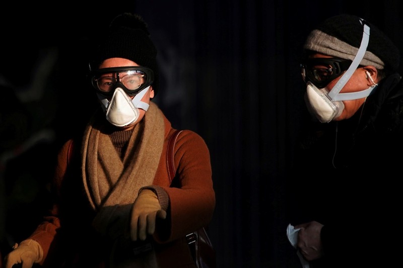 Hai hành khách đeo kính phòng hộ lao động và mặt nạ. (Ảnh: Reuters)