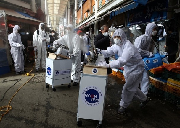Dịch bệnh COVID-19 lây lan mạnh ở Hàn Quốc, các nhân viên phòng dịch phun thuốc khử trùng trong chợ (Ảnh: Getty).