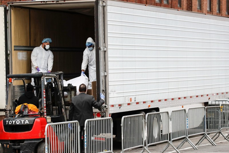 Cửa sau xe mở và một chiếc xe nâng đang đưa thi thể của người quá cố vào trong xe tải đông lạnh (Ảnh: AP)