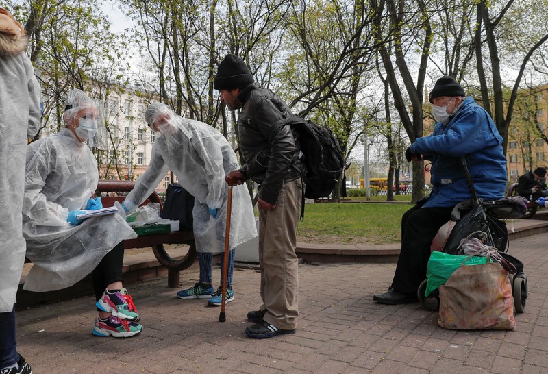 Những người tình nguyện Belarus trong trang phục phòng hộ mang vật tư y tế đến giúp đỡ người vô gia cư trên đường phố phòng dịch bệnh (Ảnh: Reuters).