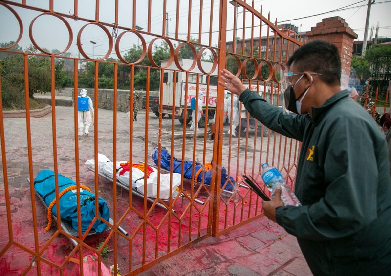 Một người Nepal vĩnh biệt những người thân trong lò thiêu qua hàng rào (Ảnh: AP).