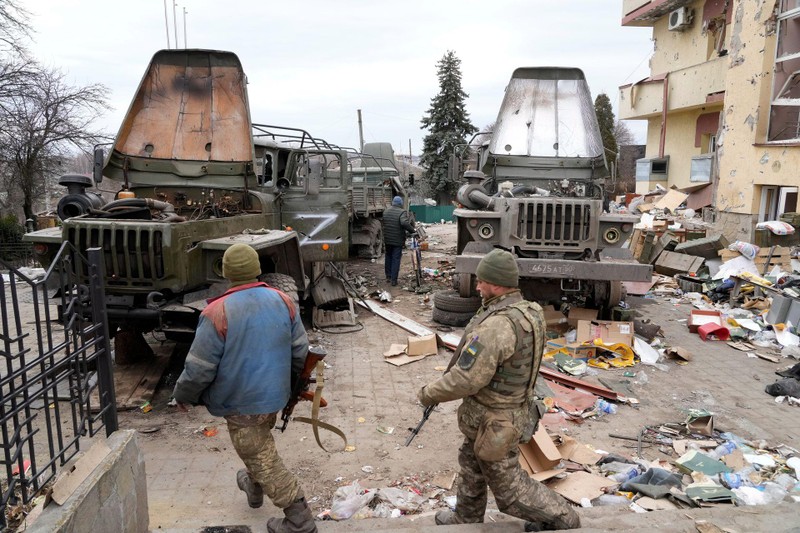 Những người lính Ukraine xem xét các xe quân sự đã bị hư hỏng bị quân Nga bỏ lại (Ảnh: AP).