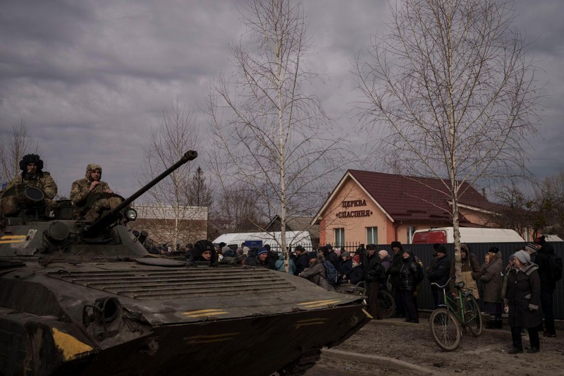 Ngày 28/3, tại thị trấn Trostsyanets, binh sĩ Ukraine ngồi trên xe thiết giáp trong khi người dân xếp hàng để được cứu viện (AP).