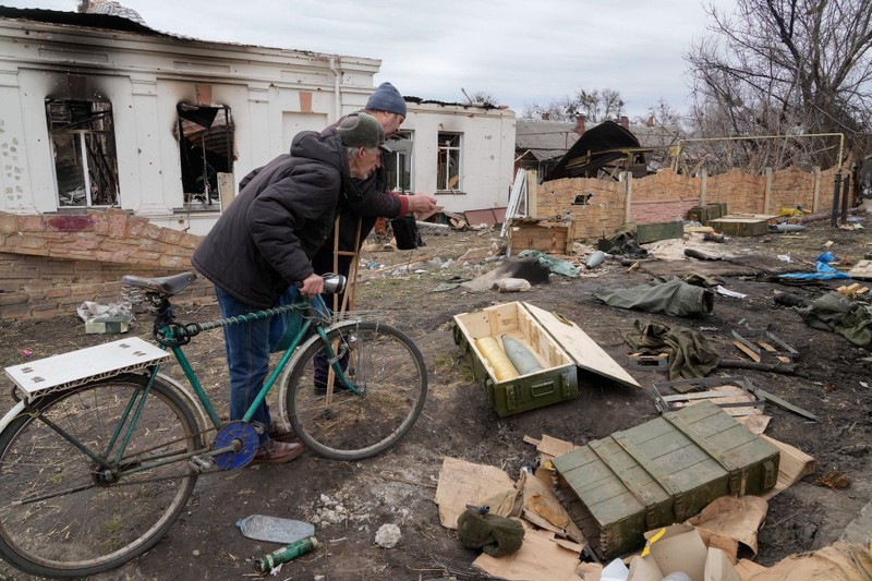 Người dân địa phương xem đạn pháo quân Nga bỏ lại sau cuộc giao tranh mới nhất ở thị trấn Trostsyanets, ngày 28/3. (AP)