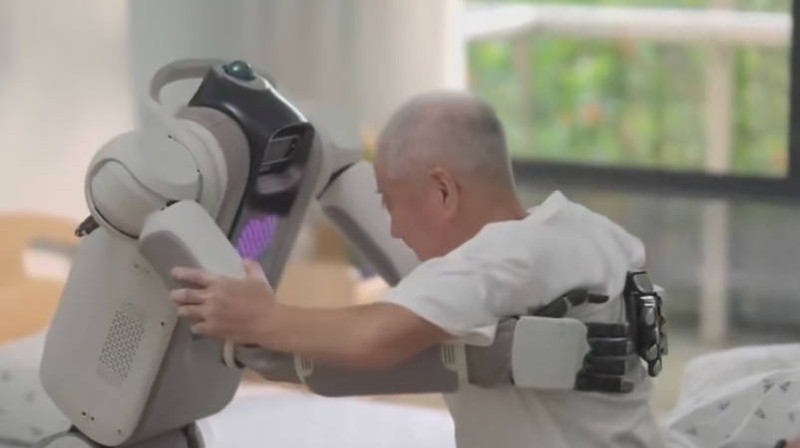 Robot dưỡng lão đỡ người già từ giường ra xe lăn. Ảnh: VCG. Diu benh nhan tu giuong len xe.jpg