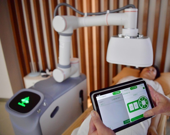 Bác sĩ sử dụng máy tính bảng để điều khiển robot xoa bóp, bấm huyệt. Ảnh: VCG. Robot can cu the trang tung nguoi.jpg