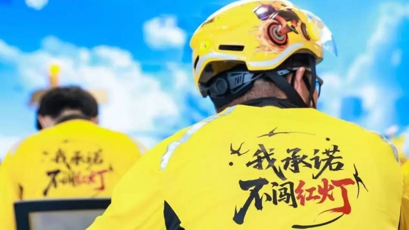Shipper mặc áo in dòng chữ "Tôi cam kết không vượt đèn đỏ". Ảnh: Singtao. ao shipper.jpg