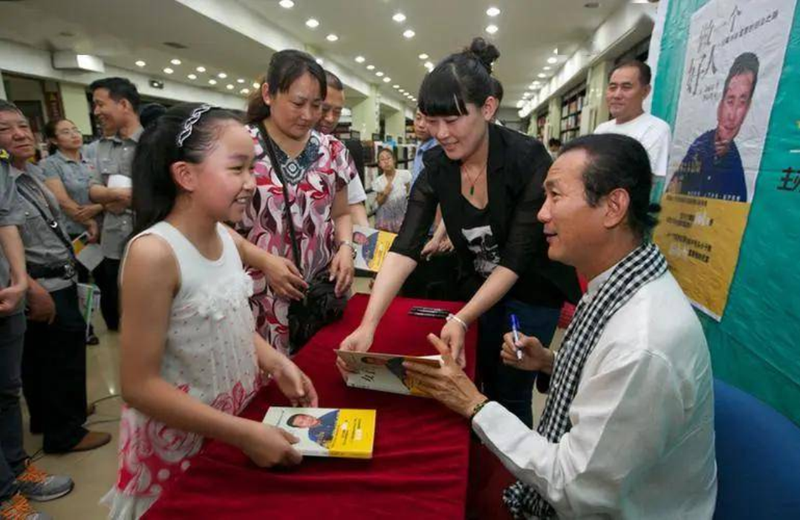 Vikrom Kromadit ký tên tặng sách cho độc giả. Ảnh: Sohu. Ky ten tang sach.png