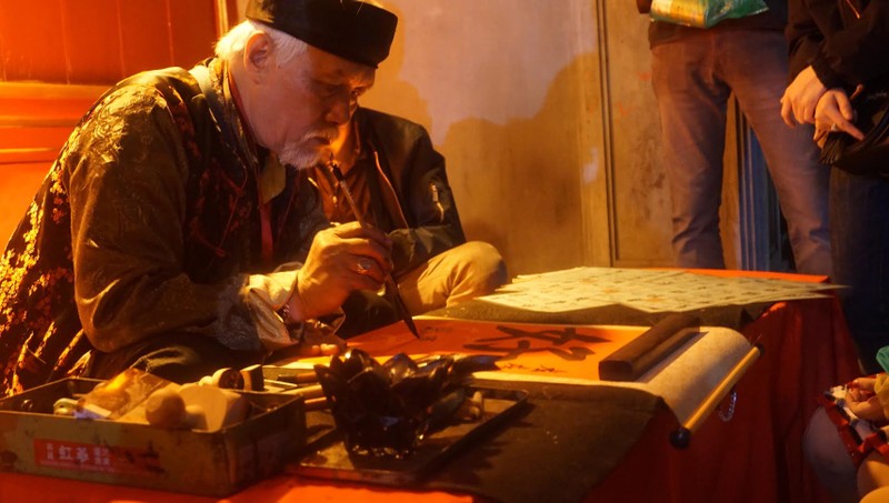 Quầy thư pháp ngay trước cổng Đền cũng rất đông khách.