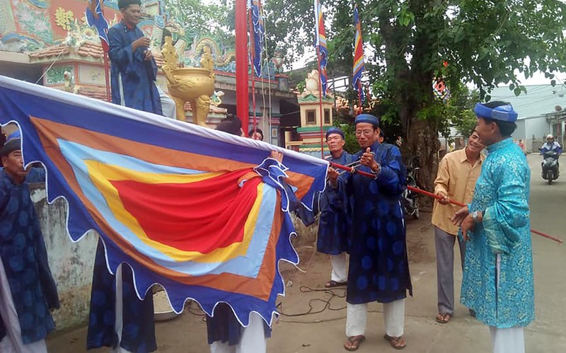 Các bậc cao niên trong chi tộc buộc cờ Tổ quốc và cờ phướn vào đầu cây nêu