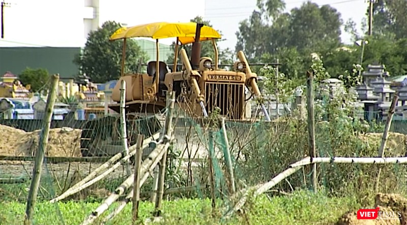 Máy móc xen lẫn ruộng hoa màu và nghĩa địa của người dân địa phương Máy móc xen lẫn ruộng hoa màu và nghĩa địa của người dân địa phương