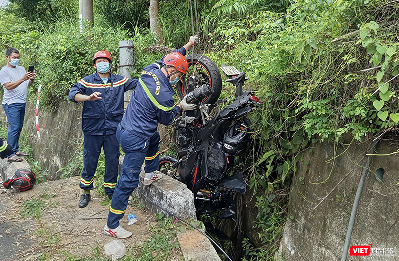 Lực lượng cứu hộ đang cẩu chiếc mô tô của nạn nhân từ mương thoát nước. vt_du khach tu nan 2.png