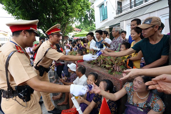 Cảnh sát chuyển nước uống cho người dân ngồi xem đoàn diễu binh trên phố Nguyễn Thái Học. Ảnh: Bá Đô. Cảnh sát chuyển nước uống cho người dân ngồi xem đoàn diễu binh trên phố Nguyễn Thái Học. Ảnh: Bá Đô.