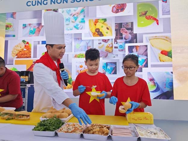Em nhỏ say sưa tạo hình chiếc bánh mỳ đầu tiên của mình. (Ảnh: VNA). Em nhỏ say sưa tạo hình chiếc bánh mỳ đầu tiên của mình. (Ảnh: VNA).